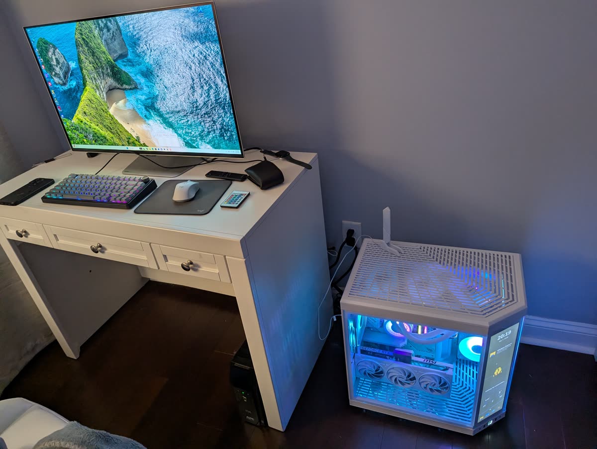 Custom white gaming PC build with RGB lighting and liquid cooling beside a tidy desk setup