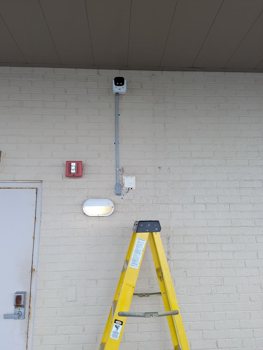 Security camera mounted on conduit above a doorway after installation