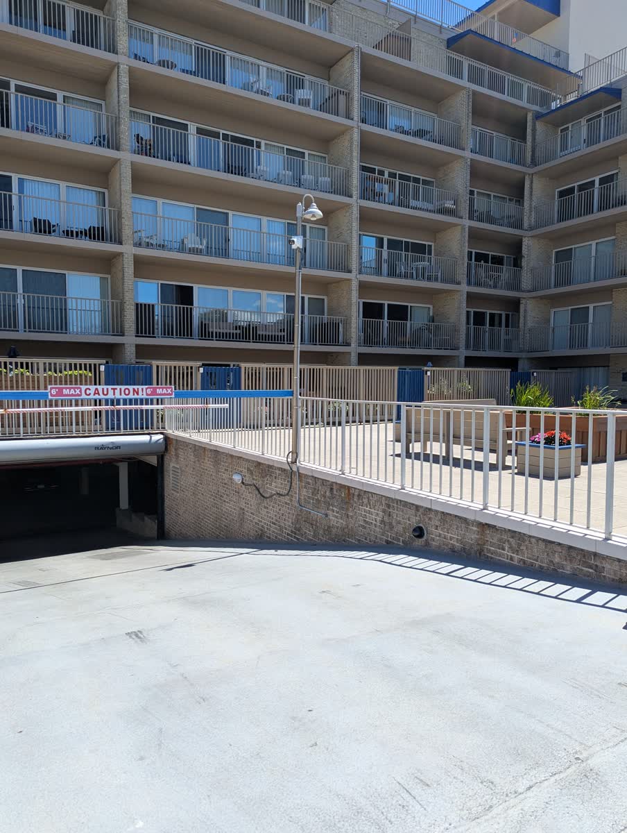 Parking garage ramp exit at Patrician Towers with a pole-mounted security camera overlooking the entrance and rooftop courtyard