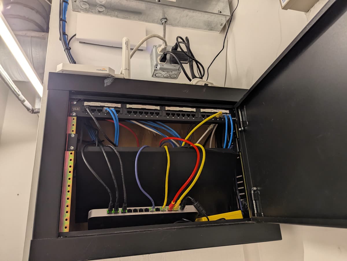 Finished network cabinet with color-coded cables into a Meraki MX68 firewall and Cradlepoint LTE router