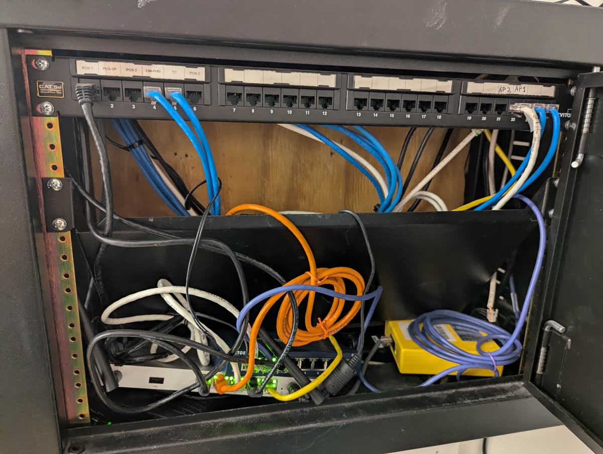 Network cabinet mid-installation with labeled patch panel and undressed cables
