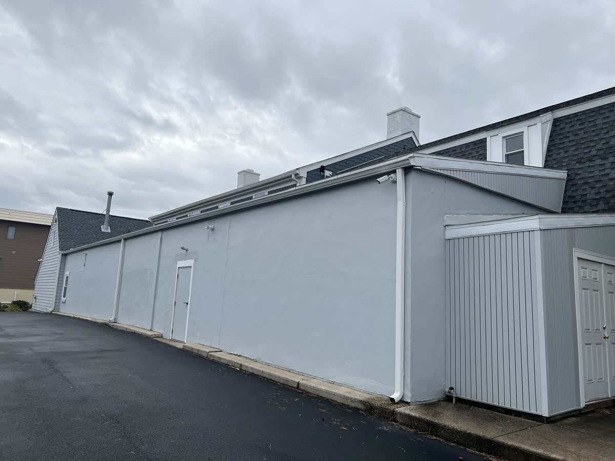 Weatherproof security camera mounted on the rear-left exterior wall of Venus Nails Salon overlooking the back parking area